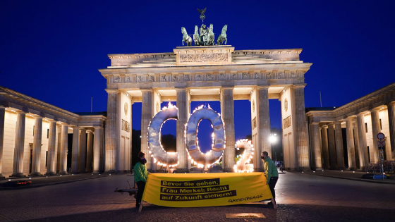 A CO2 sign stands in front of the Brandenburg Gate with flames coming out of it