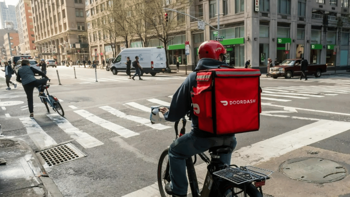 A DoorDash worker rides bike to make delivery