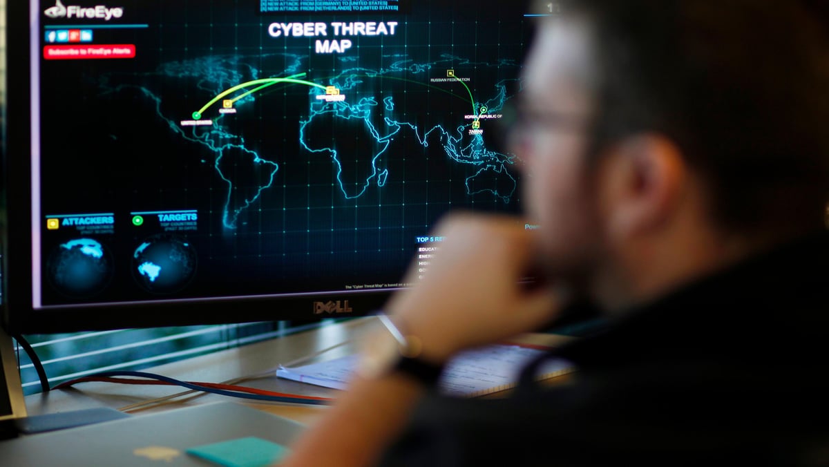 A FireEye information analyst works in front of a screen showing a near real-time map tracking cyber threats at the FireEye office in Milpitas, California