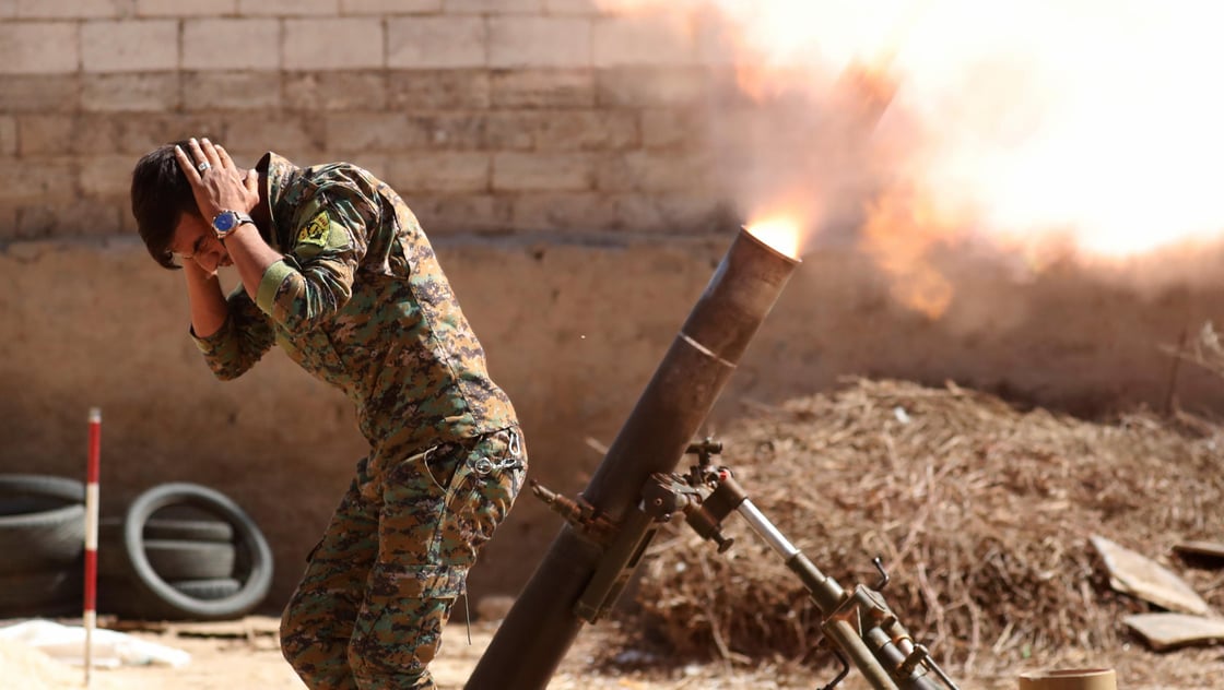 A Kurdish fighter from the Peoples Protection Units (YPG) fires a 120 mm mortar round in Raqqa, Syria