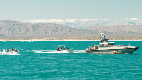 A Mexican Navy vessel is seen next to masked men on skiffs fishing illegally inside the Vaquita Refuge