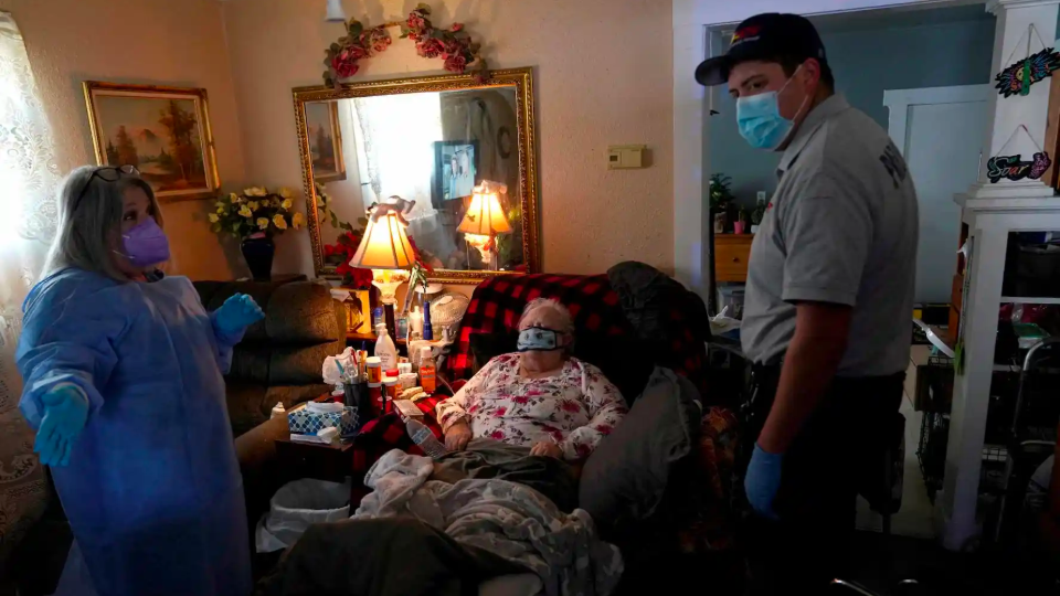 A REACT EMS paramedic talks with a home health nurse in the home of an 82 year old woman