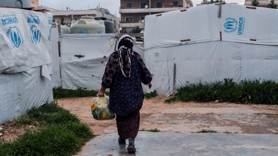 A Syrian refugee walks near tents at an informal settlement in Lebanon
