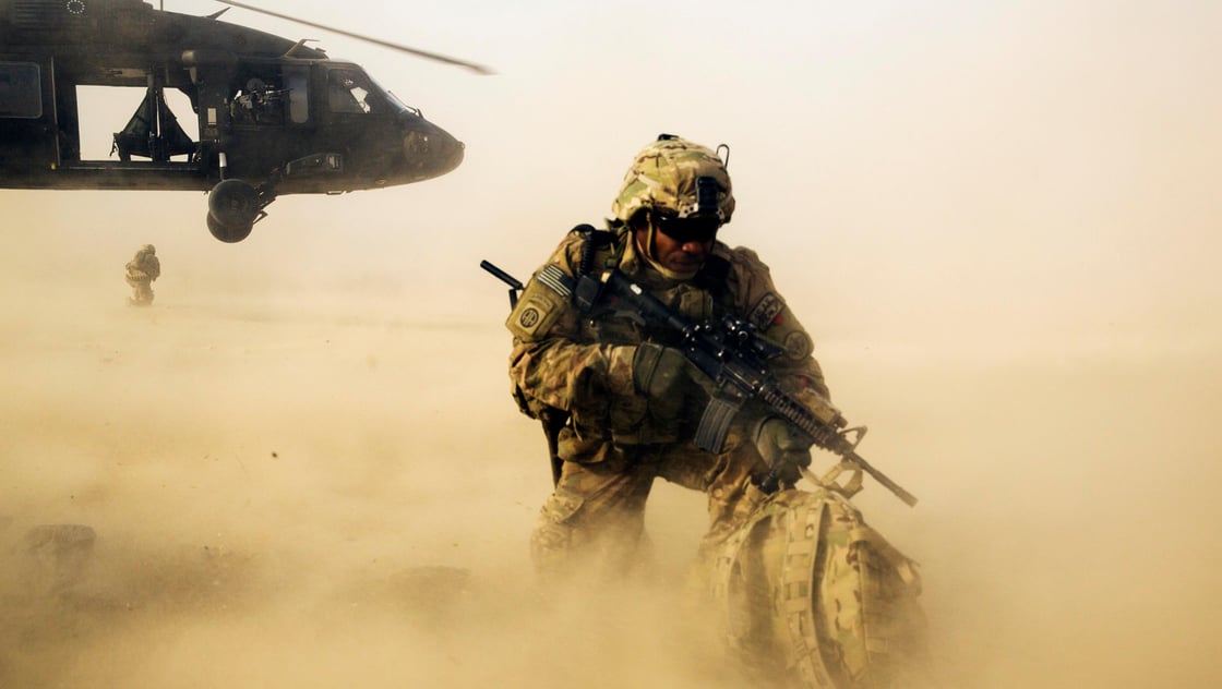 A U.S. soldier from the 3rd Cavalry Regiment shields himself from the rotor wash of a UH-60 Blackhawk helicopter