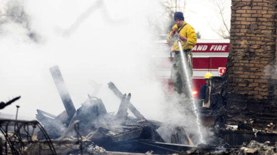 A West Metro Wildland crew member extinguishes a fire at a home in the aftermath of the Marshall Fire in Louisville, Colorado, U.S