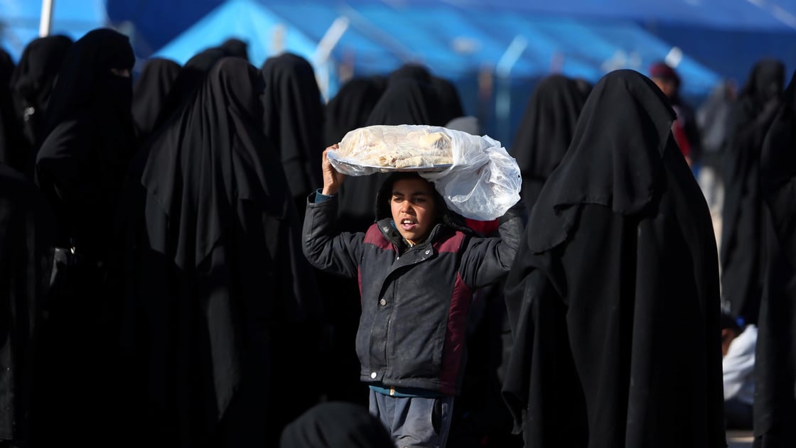 A boy carries bread on his head at al-Hol displacement camp in Hasaka governorate