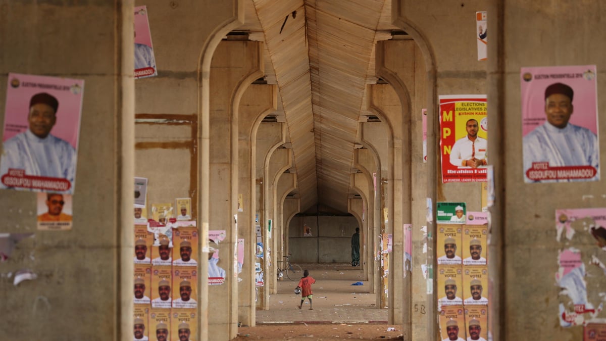 A boy walks past electoral campaign posters for presidential candidates in Niamey, Niger