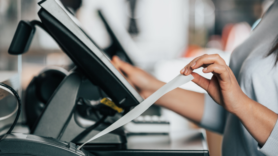 A cashier pulls a receipt out of the printer. 