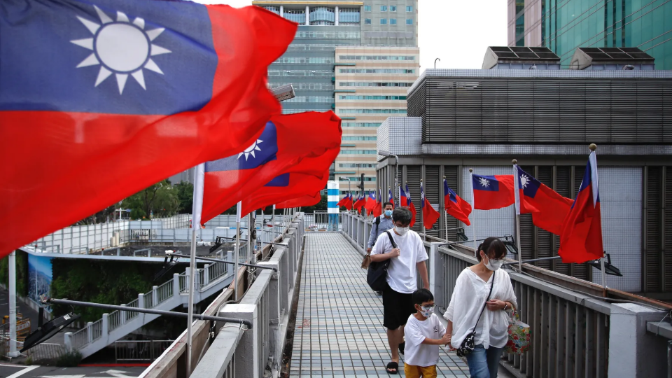 A child and his guardian walk across a footbridge in Taipei, where Taiwan flags flutter ahead of the island’s national day