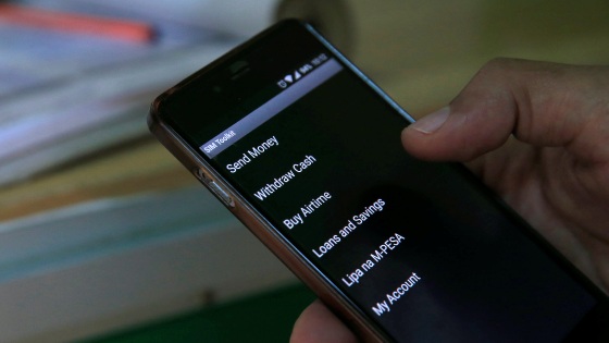 A customer conducts a mobile money transfer, known as MPesa, at a Safaricom agent stall in downtown Nairobi