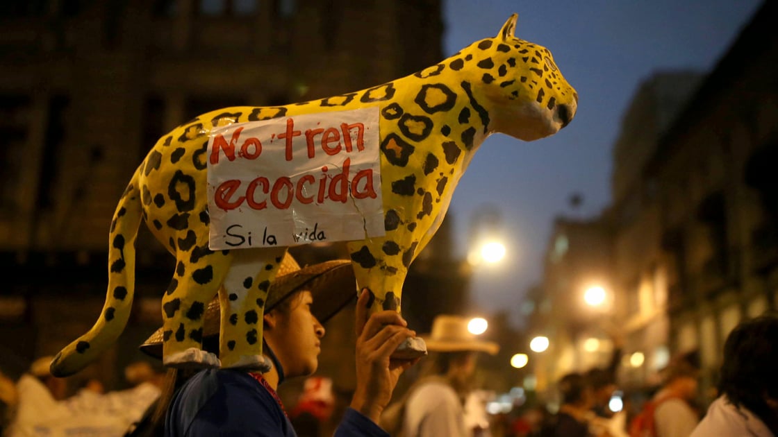 A demonstrator holds a papier-mache jaguar