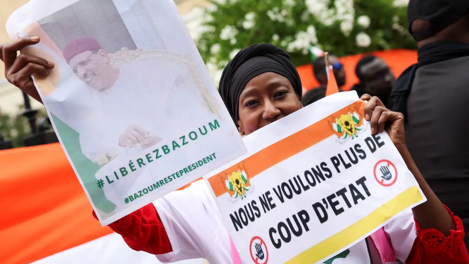 A demonstrator holds placards, one of them reading 