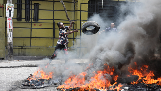 A demonstrator throws a tire into a burning roadblock during protests demanding that the government of Prime Minister Ariel Henry do more to address gang violence