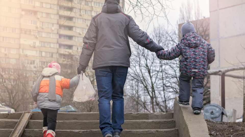 A family walks up the stairs together with groceries.