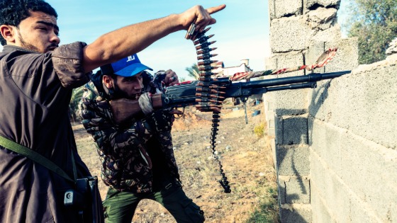 A fighter of Brigade 610 (GNA) fires with his machine-gun while his comrade points his finger towards the enemy