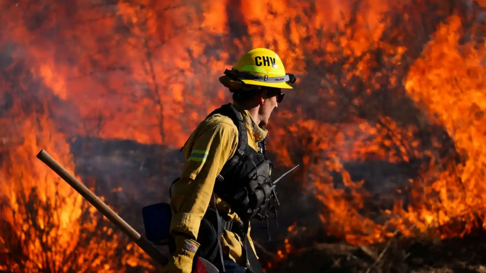 A firefighter works to extinguish the Highland Fire, a wind driven wildfire near Aguanga, California