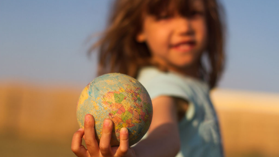 A girl holds a globe in her hand