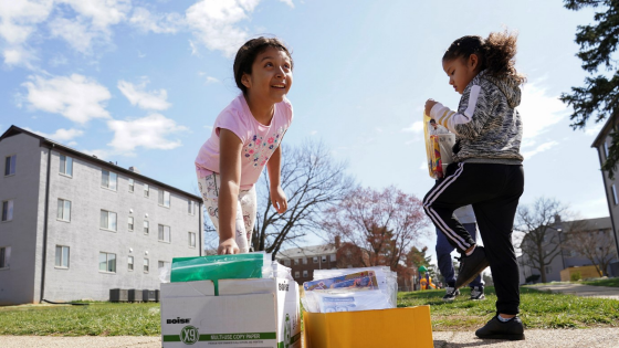 A girl reaches for a bag of school supplies delivered by volunteers in a low income neighborhood of Falls Church