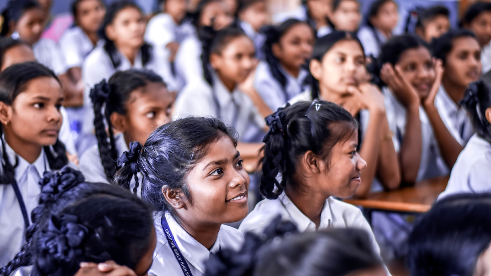 A group of Indian girls sit in a classroom together.