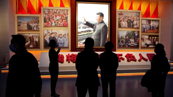 A guide talks to visitors in front of images of Chinese President Xi Jinping