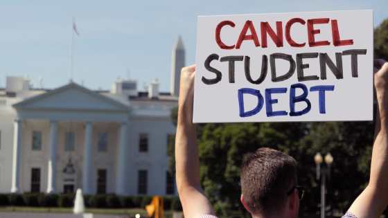 A man holds a cancel student debt sign in front of the White House