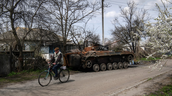 A man rides a bicycle past the debris of Russian military machinery