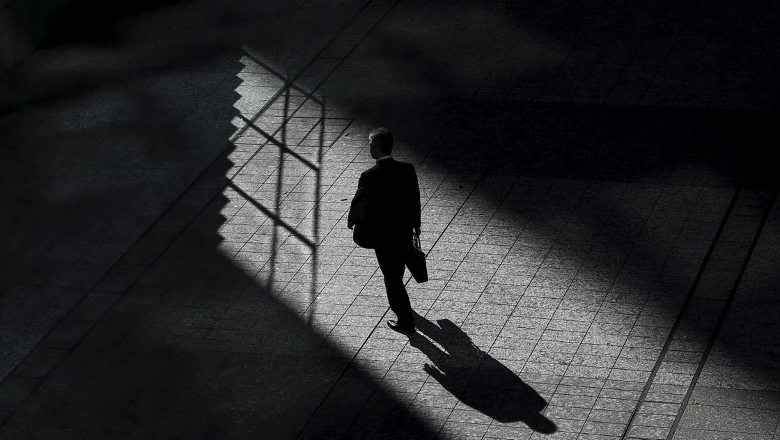 A man walks on a street between buildings