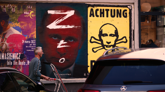 A man walks past a poster with an image of Russian President Vladimir Putin painted with the Russian Z sign