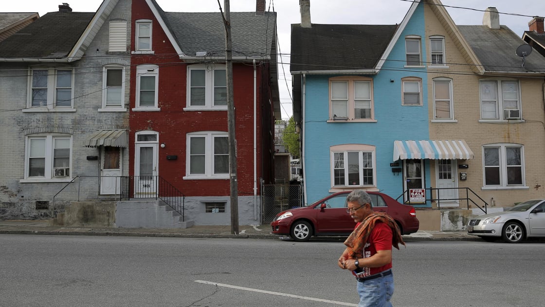 A man walks past multi-colored homes that face the now-closed Bethlehem Steel mill in Bethlehem, Pennsylvania