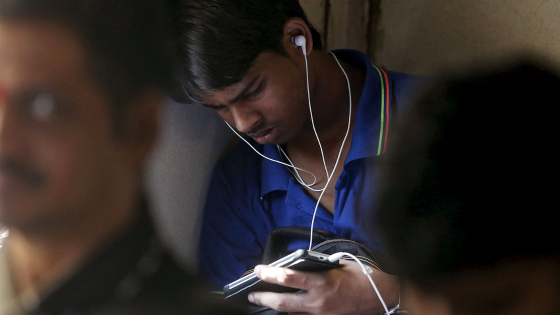 A man watches a video on his mobile phone as he commutes by a suburban train in Mumbai