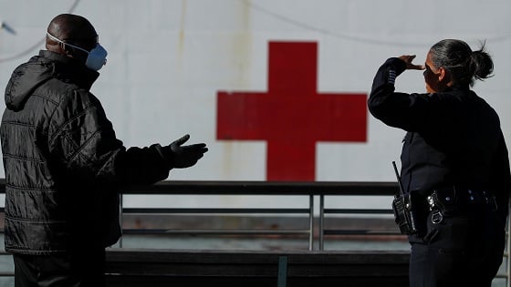 A man wearing a mask and gloves talks with a police officer in Los Angeles