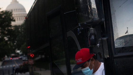 A migrant exits a bus during early morning hours following a travel from Texas