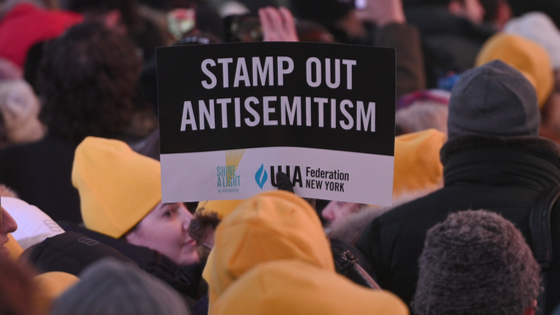 A person holds up a sign denouncing antisemitism at the Shine A Light On Antisemitism event in Times Square.