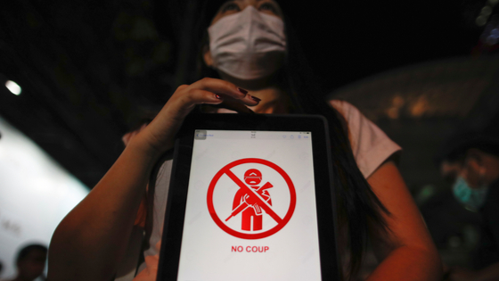 A person holds up a tablet as Myanmar citizens living in Thailand protest against the military coup