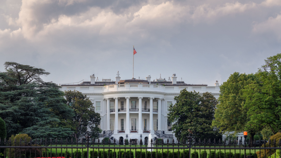 A picture of the front of the White House on a partly cloudy day.