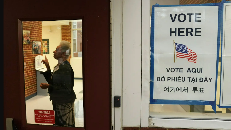 A polling station worker directs a voter to fill out their ballot on Election Day in Falls Church, Virginia