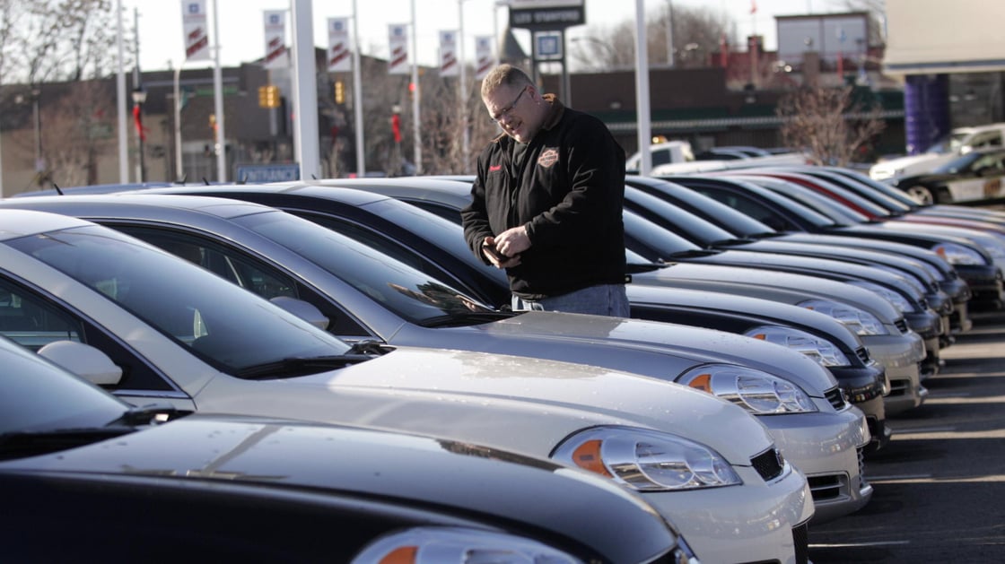 A potential customer looks at a 2009 Chevrolet Impala sedan at a car dealership in Dearborn