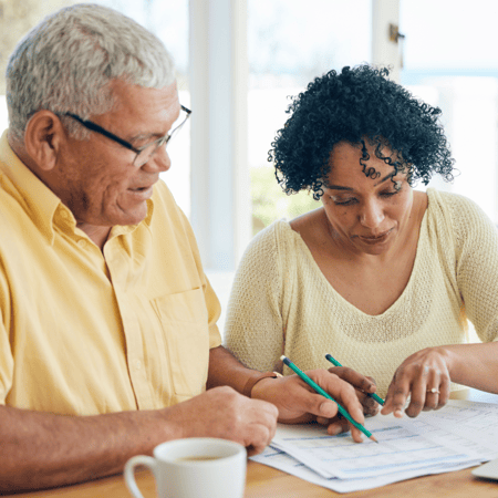 A senior couple works on paperwork together in their home.