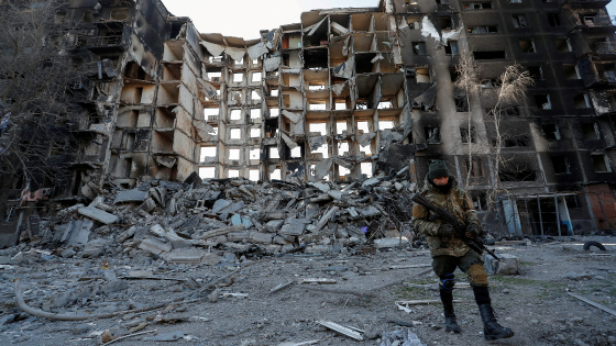 A service member of pro-Russian troops walks near an apartment building destroyed in the course of Ukraine-Russia conflict