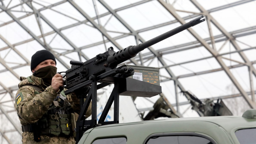 A serviceman stands behind a machine gun mounted on a Ford pickup truck