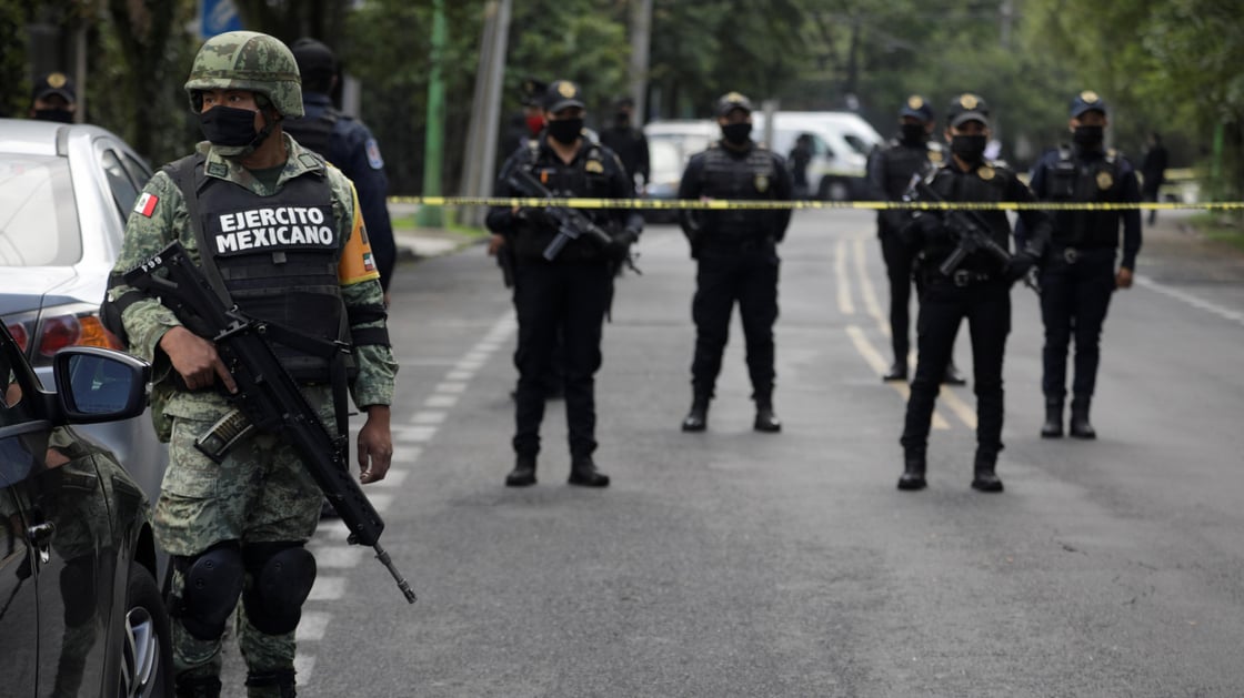 A soldier stands near police officers guarding a crime scene following an assassination attempt of Omar Garcia Harfuch