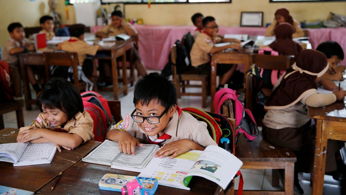 A student reacts to the camera as a teacher teaches the 2013 curriculum inside a classroom at Cempaka Putih district in Jakarta