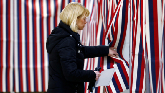 A voter enters the voting booth to mark her ballot with her vote in New Hampshire.