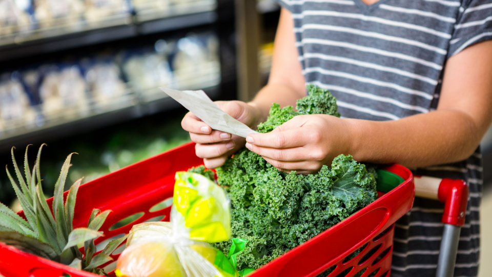 A woman checks her shopping list in a grocery store.