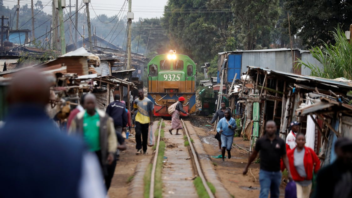 A woman crosses a railway track just as a train approaches a makeshift train station in the Kibera slum of Nairobi