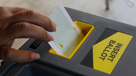 A woman inserts her ballot into an intake machine