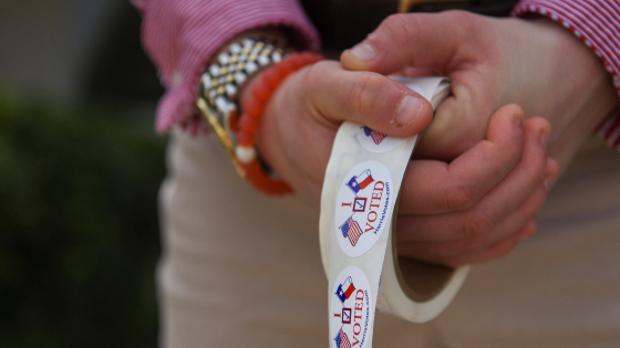 A woman passes out stickers as voters cast their ballot in the Democratic primary election at a polling station in Houston