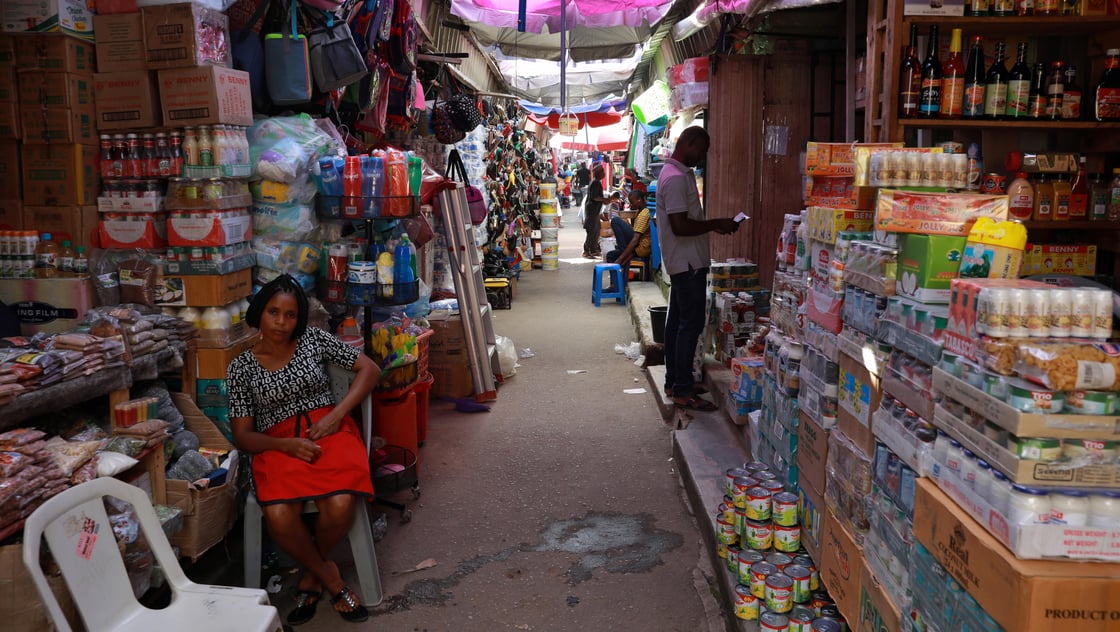 A woman sits near food items displayed for sale at a market in Abuja, Nigeria