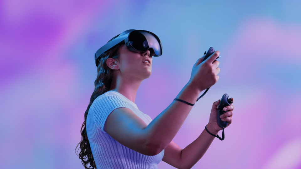 A woman uses a virtual reality (VR) headset and handhled controllers.