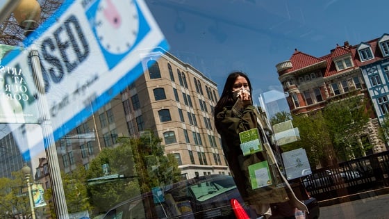 A woman walks by the closed storefront of Copenhaver stationery store during the coronavirus outbreak.